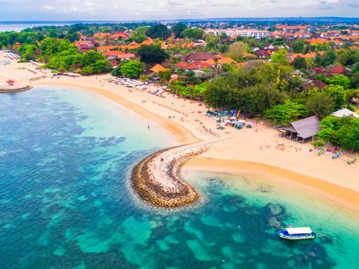 strand en turquoise zee bij Sanur op Bali, met strandtenten en een boot voor de kust.