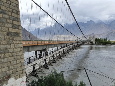 Hangbrug over een brede rivier in Baltistan, met bergen op de achtergrond tijdens de route Pakistan - Baltistan & Hunza.