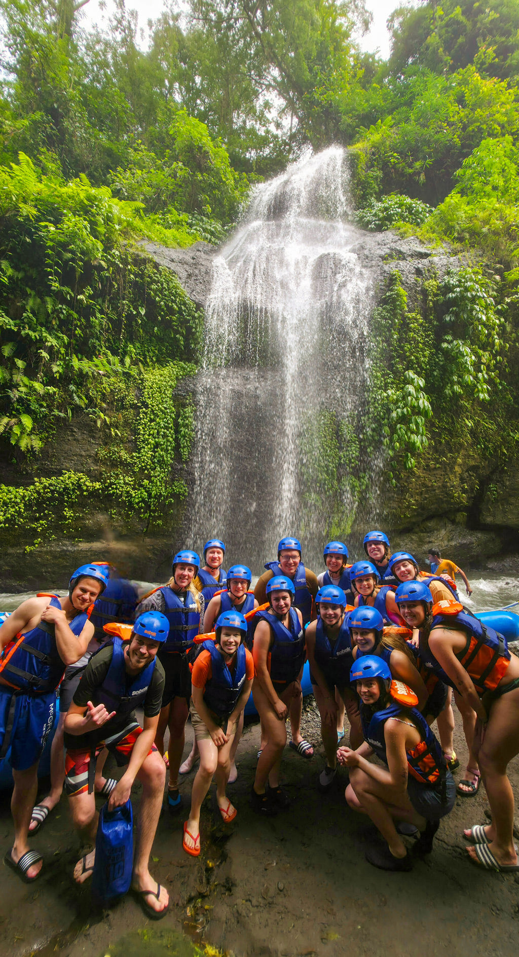 Groep reizigers met helm en zwemvest bij een waterval tijdens de 22-35ers reis Indonesië: Java en Bali.