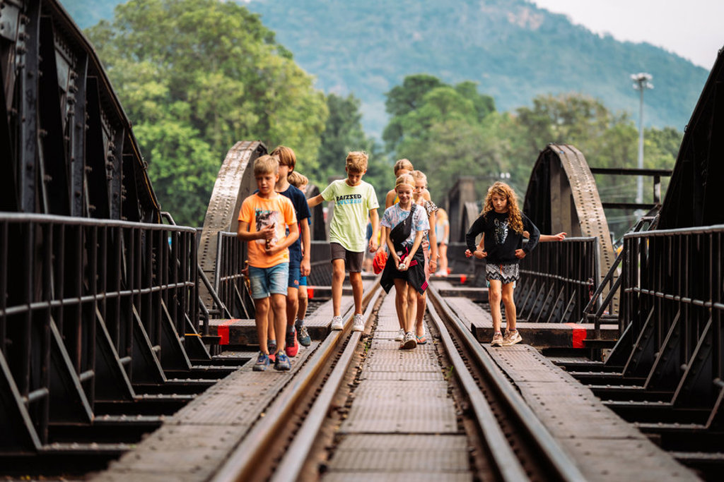 Kinderen wandelen over de River Kwai-brug in Thailand tijdens de familiereis Thailand Hoogtepunten.