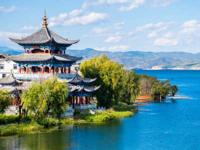 Traditionele Chinese pagode aan een helderblauw meer met bergen op de achtergrond, Route China.