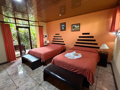 Tweepersoonskamer met twee bedden en terras bij Ara Ambigua Lodge in Costa Rica.