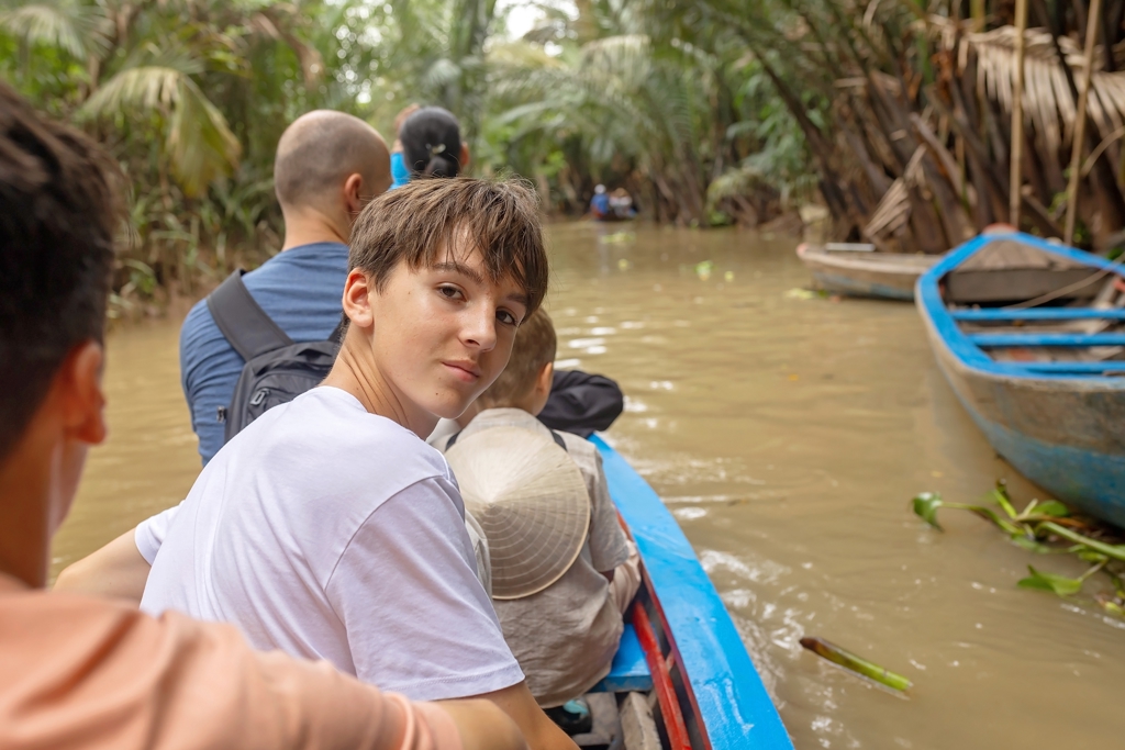 Gezin in een bootje op de Mekongdelta tussen palmen tijdens de Familiereis Vietnam Kort.