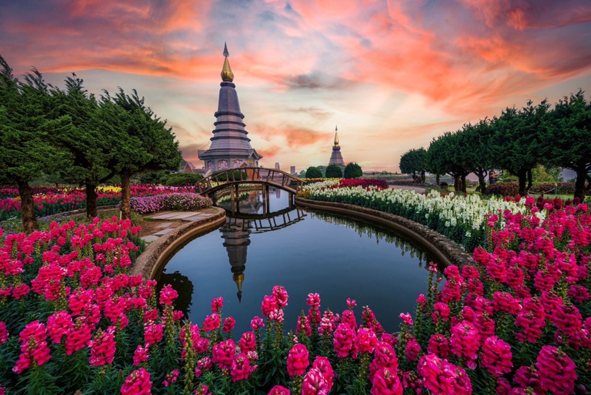 Pagode in Doi Inthanon National Park met bloemenvelden en vijver bij zonsondergang, Thailand.