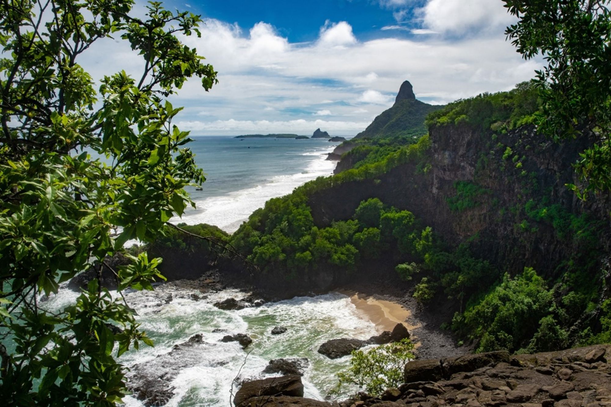 Uitzicht op de kust van Fernando de Noronha in Brazilië met groene kliffen, strand en oceaan.