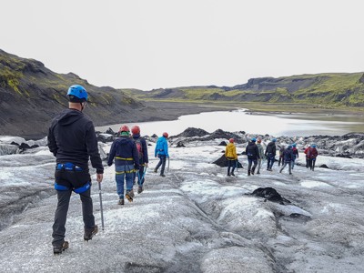 Groep wandelt met helmen en stijgijzers over een gletsjer tijdens Route IJsland, dag 3.