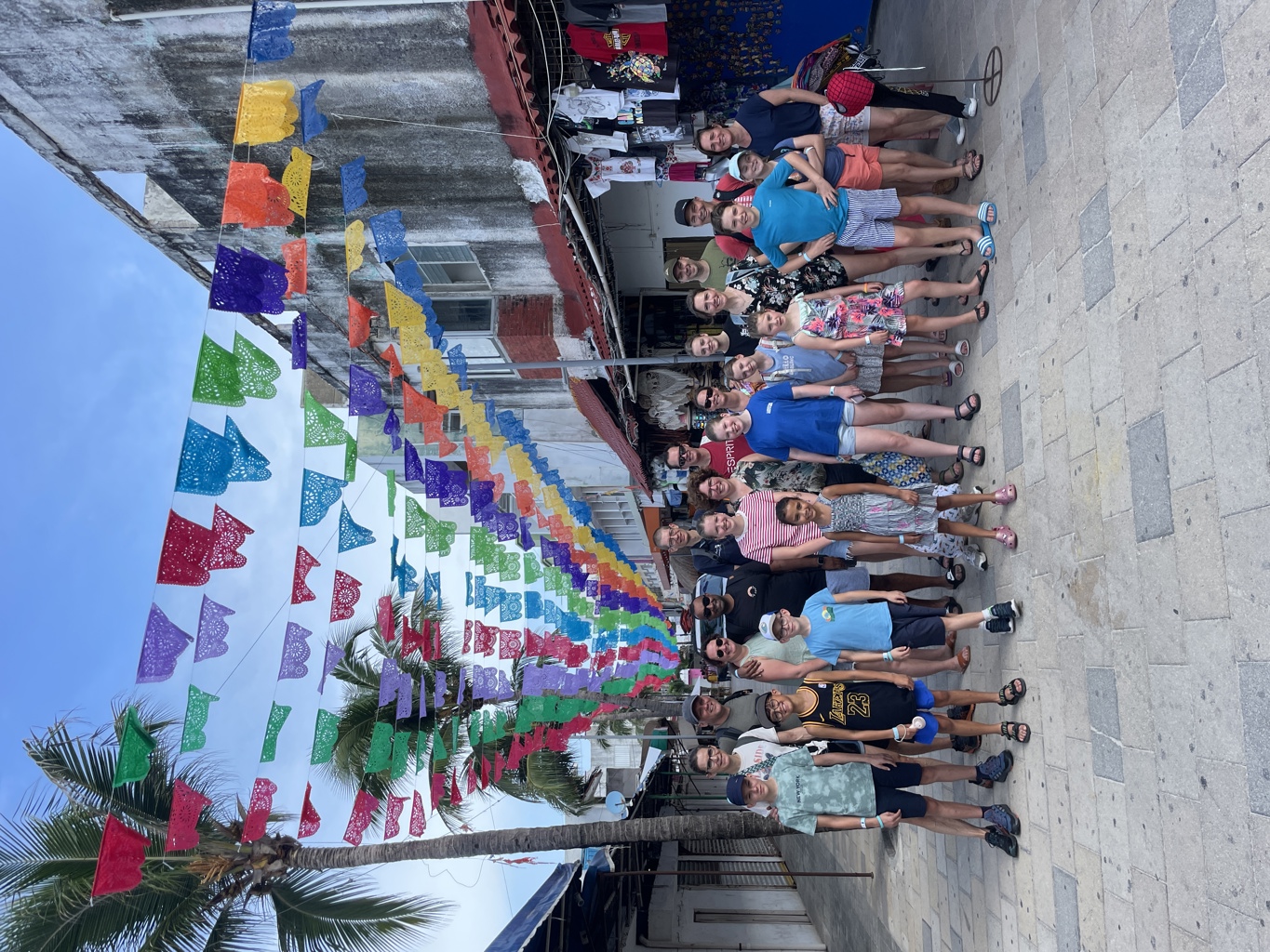 Groep reizigers tijdens Familiereis Mexico onder kleurrijke vlaggetjes in een straat met marktkramen.