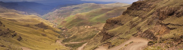 Uitzicht op de Sani Pass met een 4x4 op de kronkelende bergweg in de Drakensbergen.