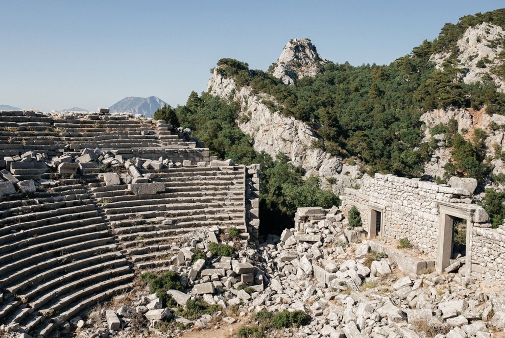 Ruïnes van een antiek amfitheater in Turkije, met stenen tribunes en rotsachtig berglandschap.
