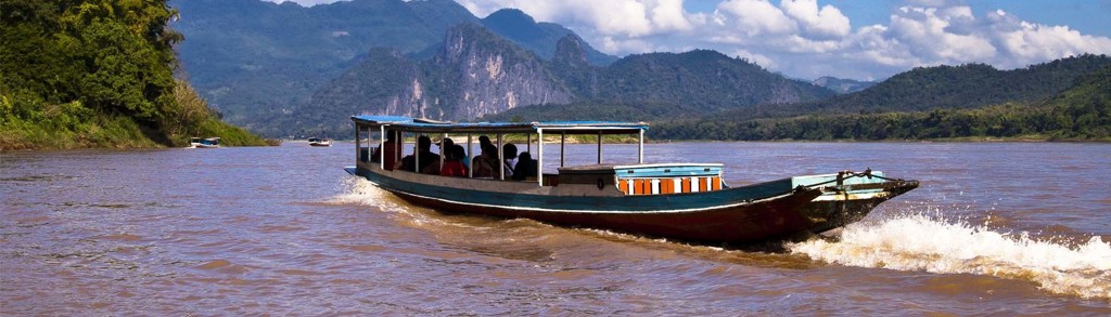 Boottocht over de Mekong tijdens familiereis Thailand, Laos en Cambodja, met groene bergen op de achtergrond.