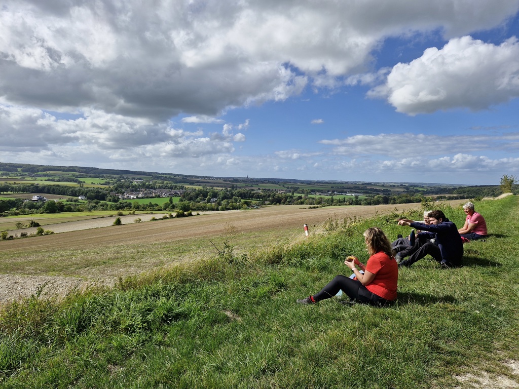 Wandelaars pauzeren op een heuvel met uitzicht over het Limburgse landschap langs de Dutch Mountain Trail.
