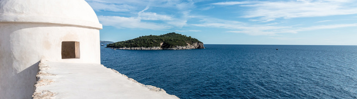 Uitzicht op de Adriatische Zee en een groen eiland vanaf een wit fort aan de Kroatische kust.