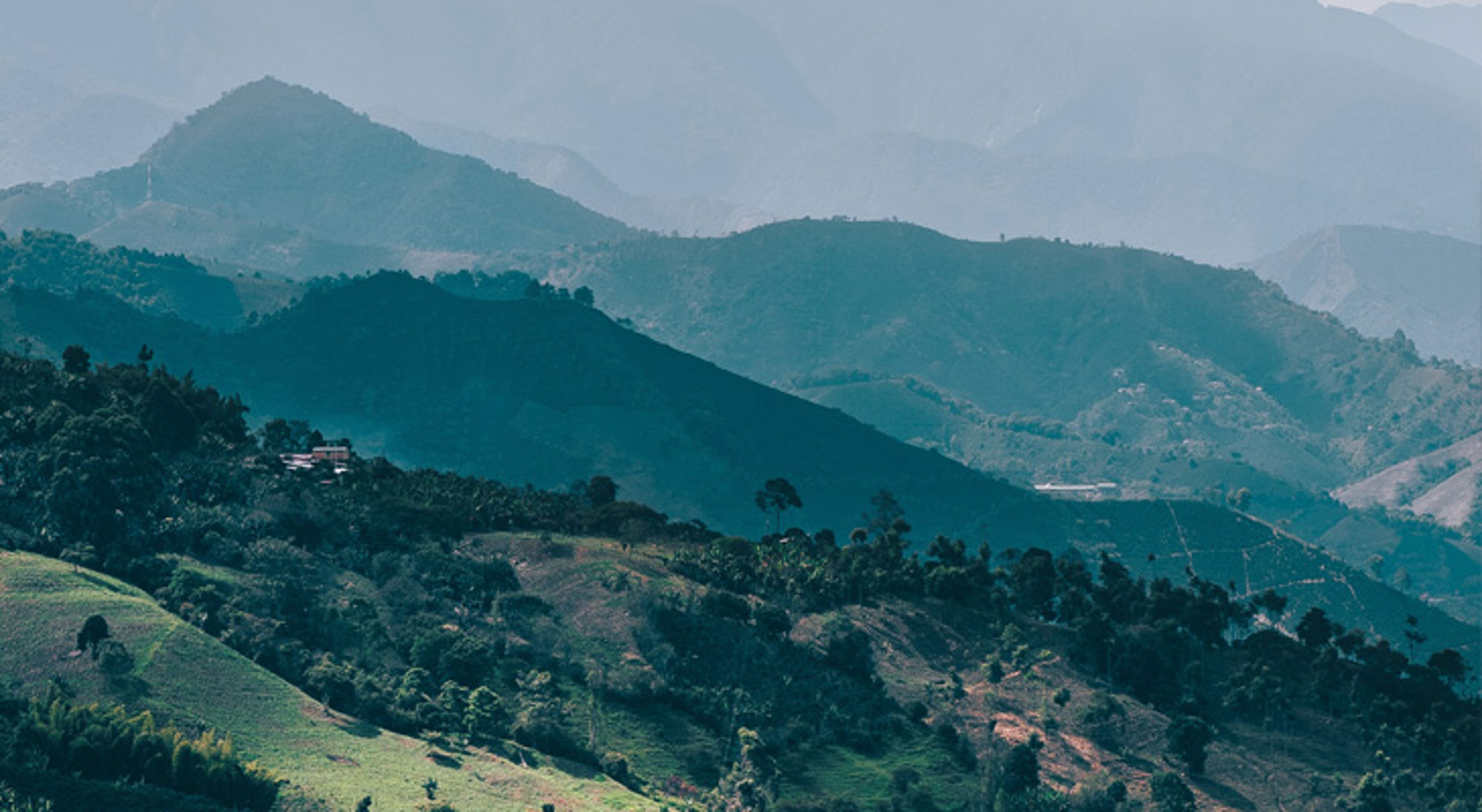 Groene berglandschappen in Colombia met mistige heuvels en valleien op de achtergrond.