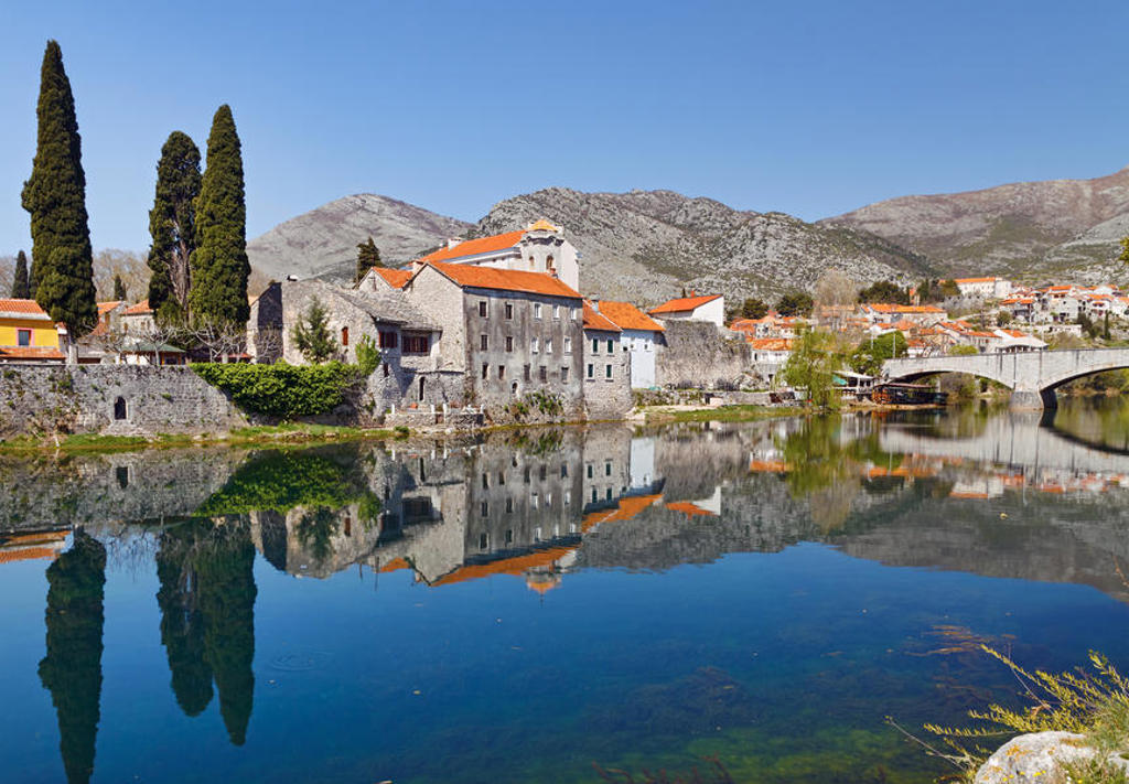 Historisch stadje in Montenegro met stenen brug en roodgedekte huizen, weerspiegeld in de rivier.