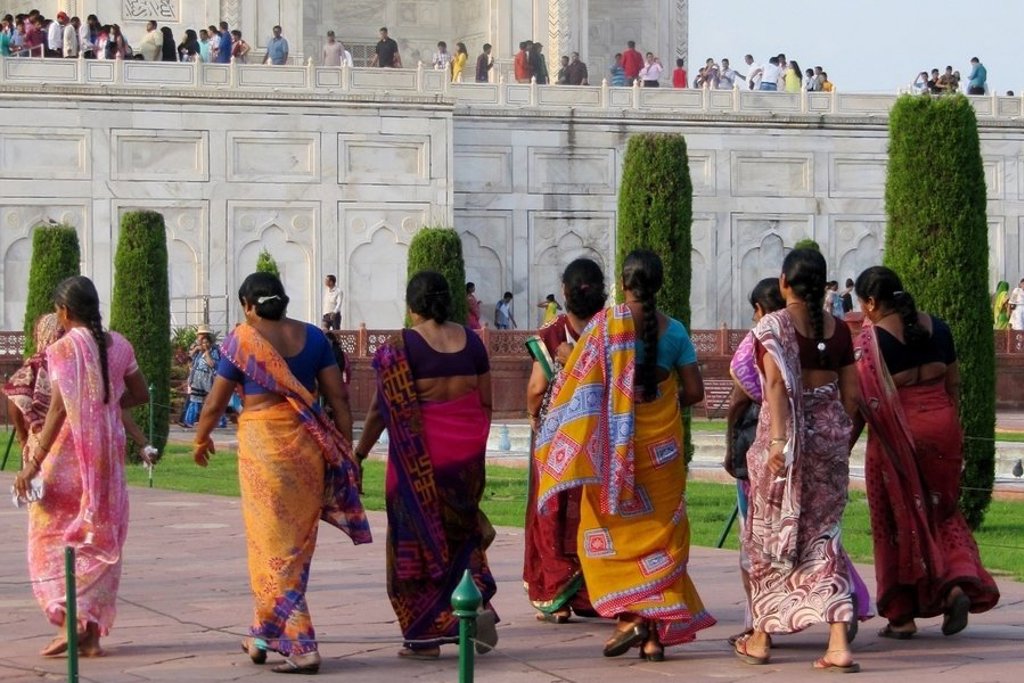 Vrouwen in kleurrijke sari’s wandelen bij de Taj Mahal in Agra, tijdens een groepsrondreis Noord-India en Nepal.