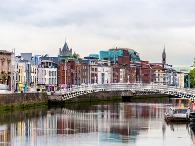 Ha’penny Bridge over de rivier de Liffey met de skyline van Dublin, Ierland.