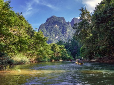 Kanotocht over een rivier door het regenwoud met kalkstenen bergen op de route Singapore, Maleisië & Thailand.