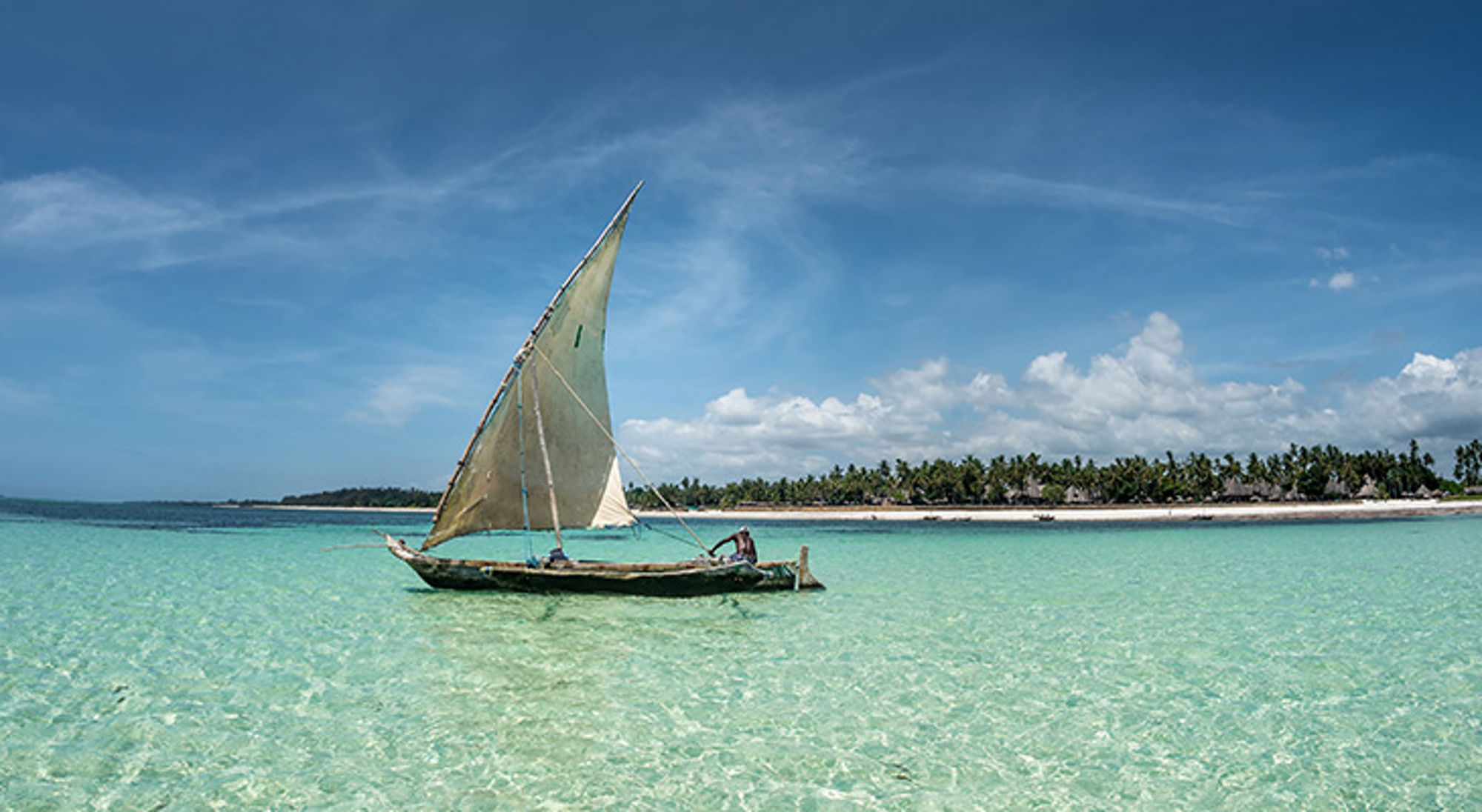 Traditionele dhow-zeilboot op turquoise zee bij tropisch strand aan de Keniaanse kust.