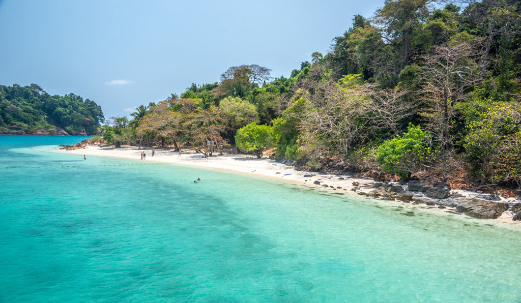 Tropisch strand met helderblauw water en groene jungle aan de kust in Thailand.