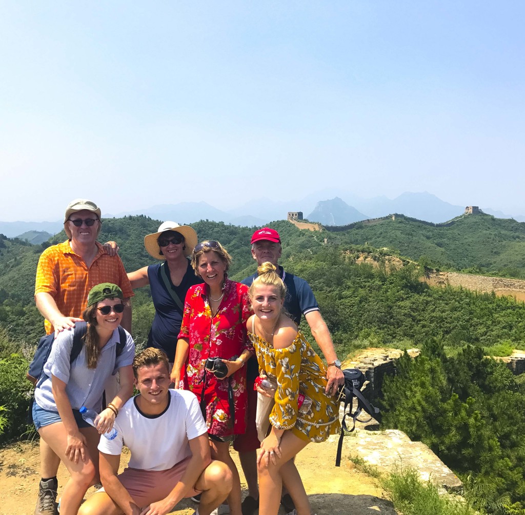 Familie poseert op de Chinese Muur tijdens familiereis China, met groene heuvels op de achtergrond.
