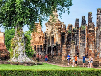 Tempelruïnes met stenen zuilen en Boeddhabeeld in Sukhothai Historical Park, Route Thailand.
