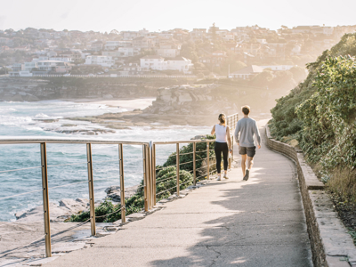 Wandelaars op het kustpad van Bondi naar Coogee in Sydney, met uitzicht op zee en kliffen.