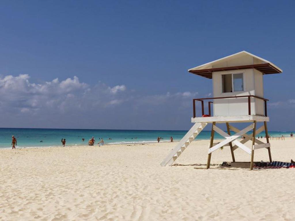 Wit zandstrand in Mexico met strandwachtpost en turquoise zee, tijdens een familiereis.