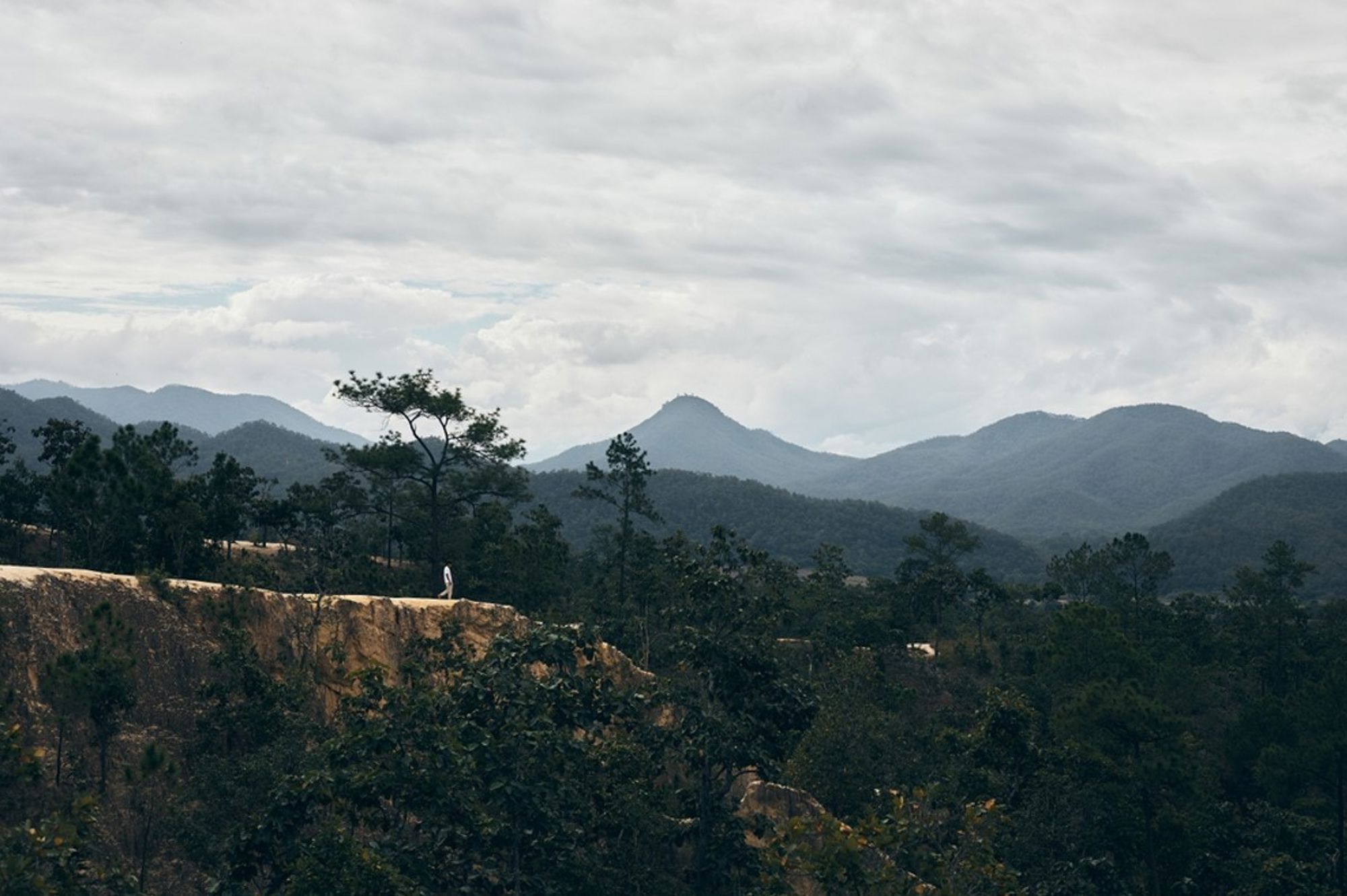 Uitzicht over beboste bergen in Thailand onder een bewolkte lucht.