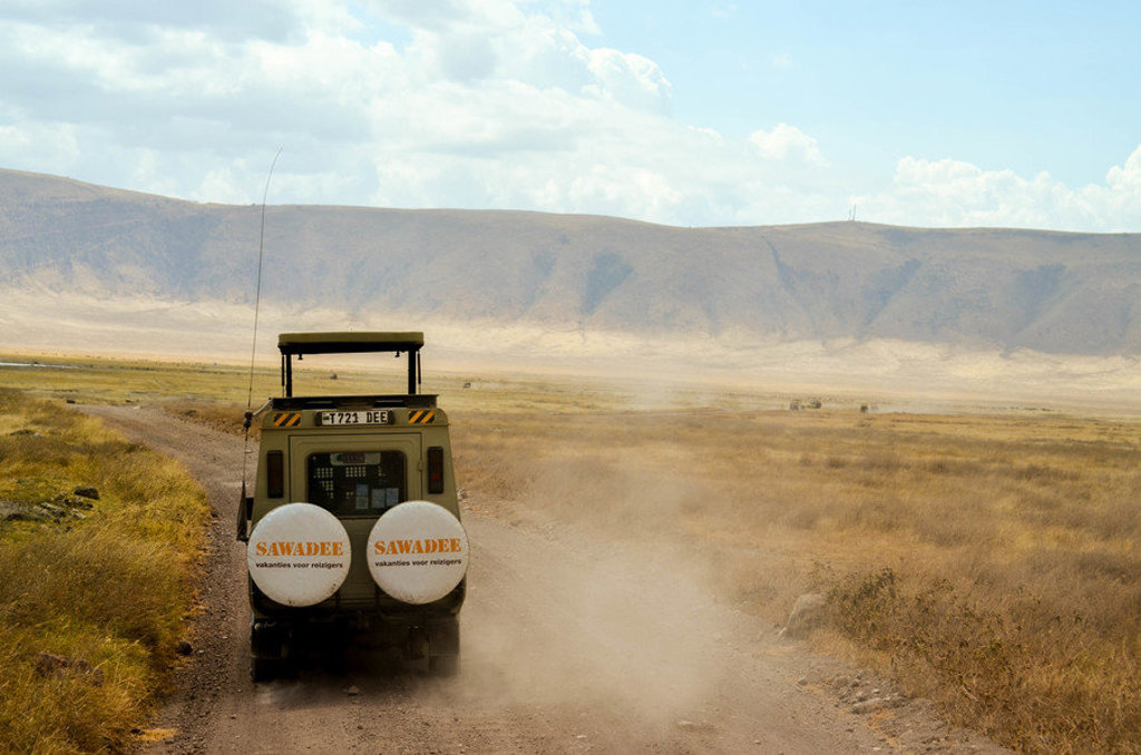 Safari-jeep op stoffige weg in Kenia of Tanzania tijdens 22-35ers groepsrondreis.