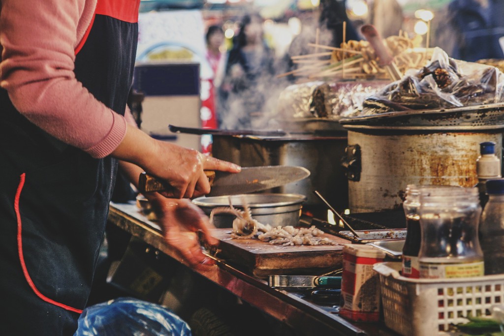 Streetfoodkraam in Zuid-Korea waar een kok verse ingrediënten snijdt en bereidt.
