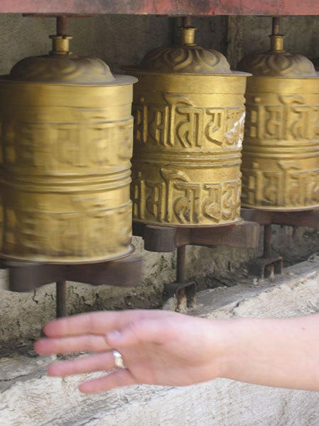 Gouden gebedsmolens in Nepal langs de Everest-trektocht, met een hand die ze draait.