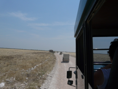 Safari-jeeps rijden over een onverharde weg door de savanne op route Victoria Falls - Windhoek.