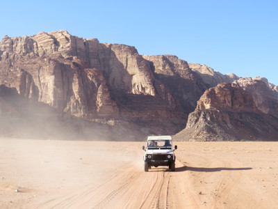 4x4 jeep safari in de Wadi Rum-woestijn in Jordanië, met rotsformaties op de achtergrond.