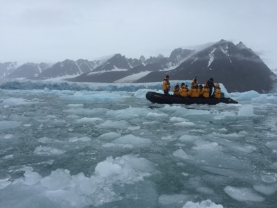 Zodiac met expeditiegangers tussen drijfijs bij gletsjer en bergen op Spitsbergen.