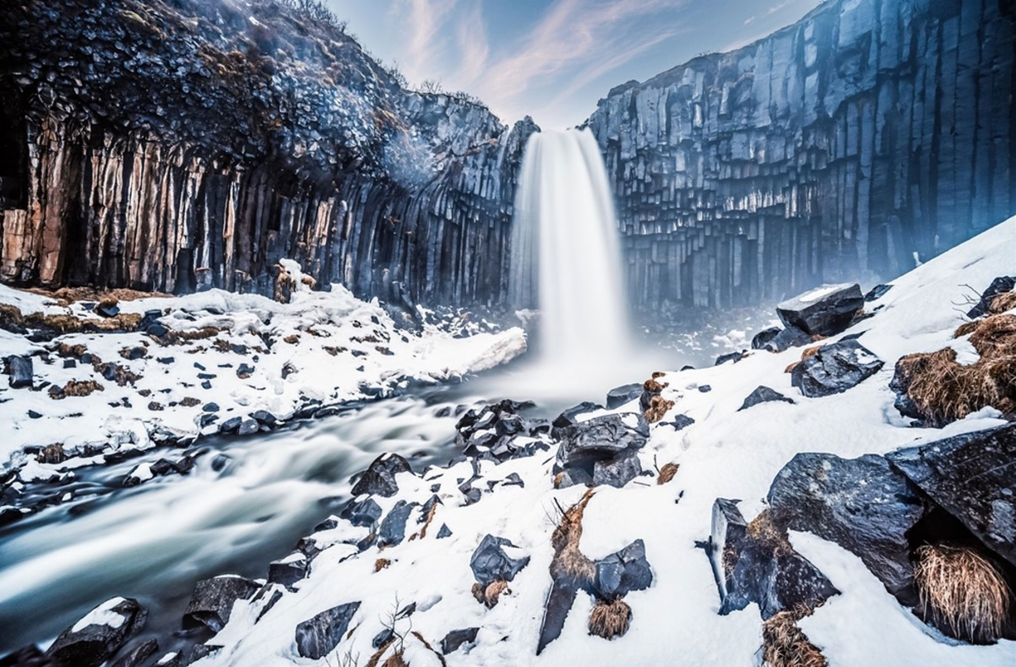 Winterse Svartifoss-waterval met basaltkolommen in Skaftafell, IJsland.