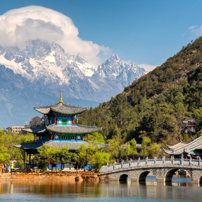 Traditionele Chinese pagode en stenen brug bij Lijiang, met besneeuwde bergen op de achtergrond tijdens groepsrondreis China.