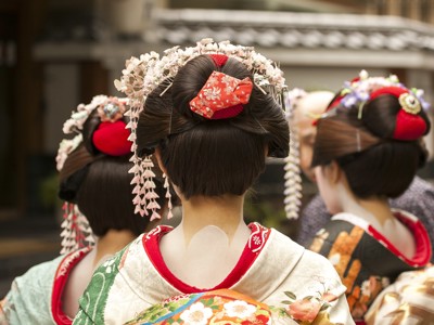 Rugaanzicht van drie vrouwen in kleurrijke kimono met traditionele haarversiering in Japan.
