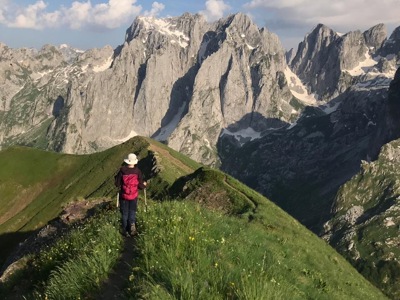Wandelaar op bergkam met uitzicht op ruige bergtoppen tijdens de Route Balkan.