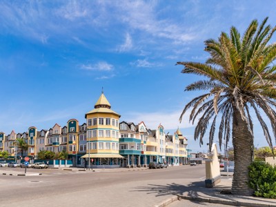 Kleurrijke koloniale gebouwen en palmbomen aan de boulevard in Swakopmund, route Victoria Falls - Windhoek.