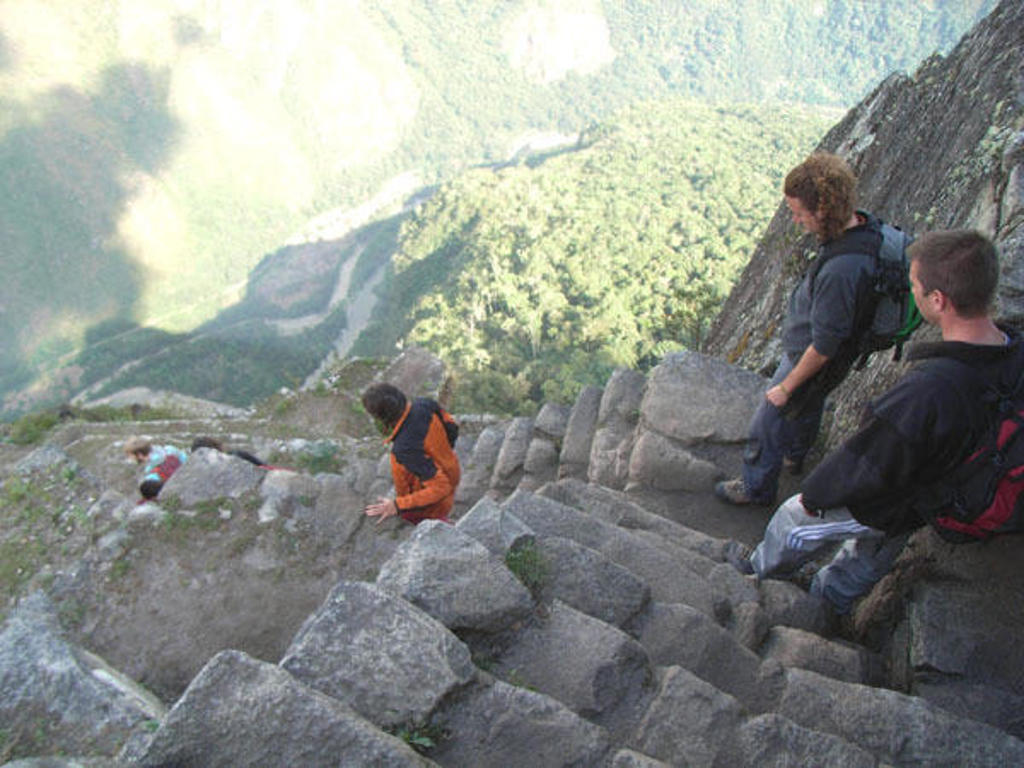 Wandelaars dalen via steile stenen trappen af langs een bergwand in de Andes.