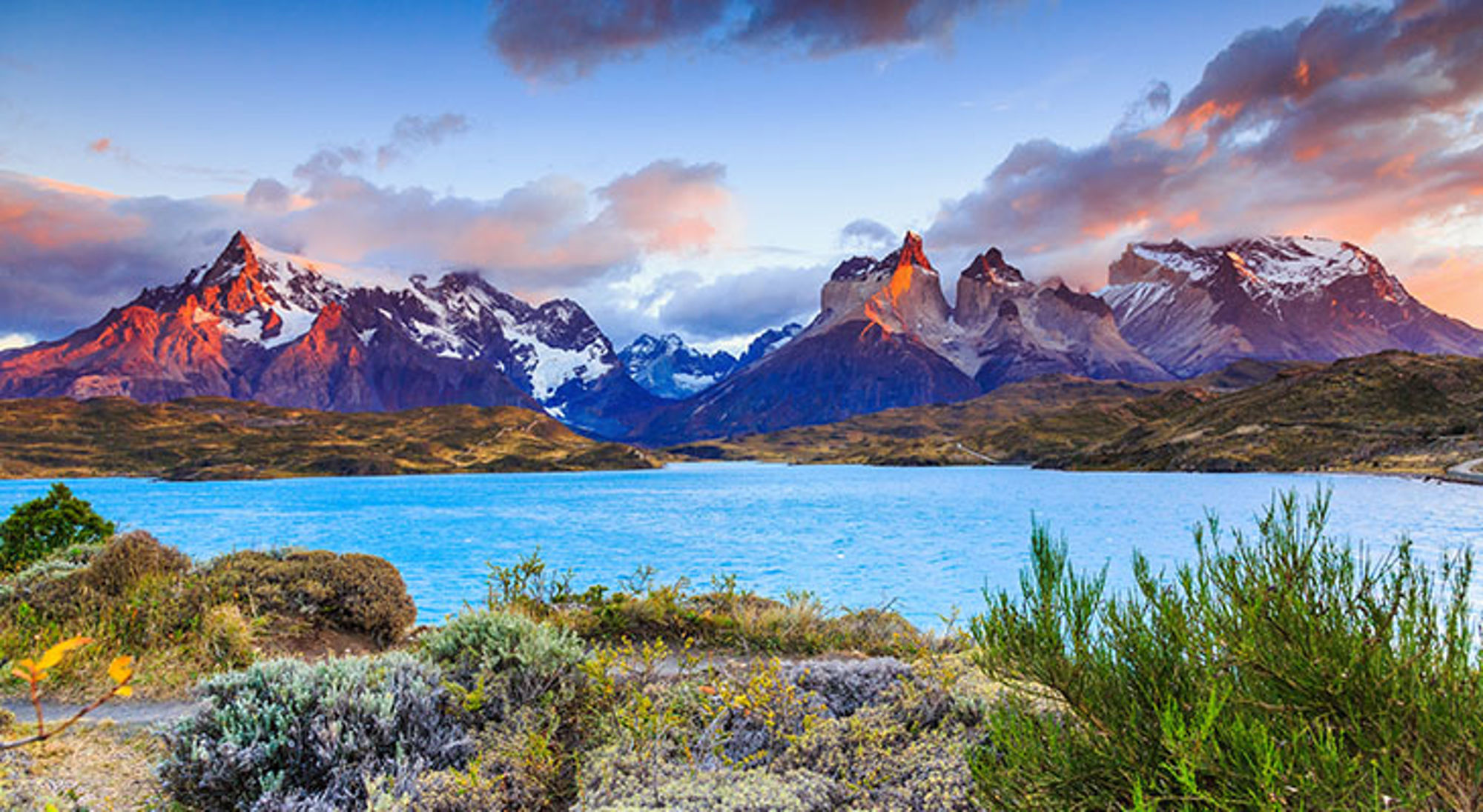 Uitzicht op de Torres del Paine-bergen en een turquoise meer in Patagonië bij zonsondergang.