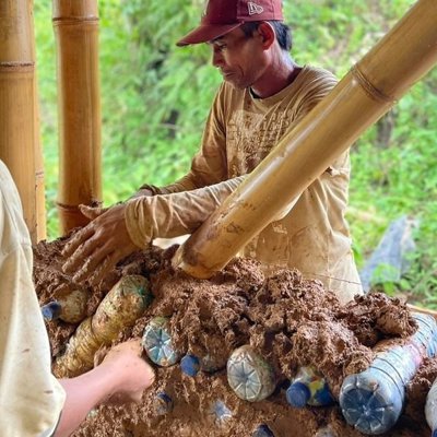 Mannen bouwen met plastic flessen en leem in het Recycling Village.