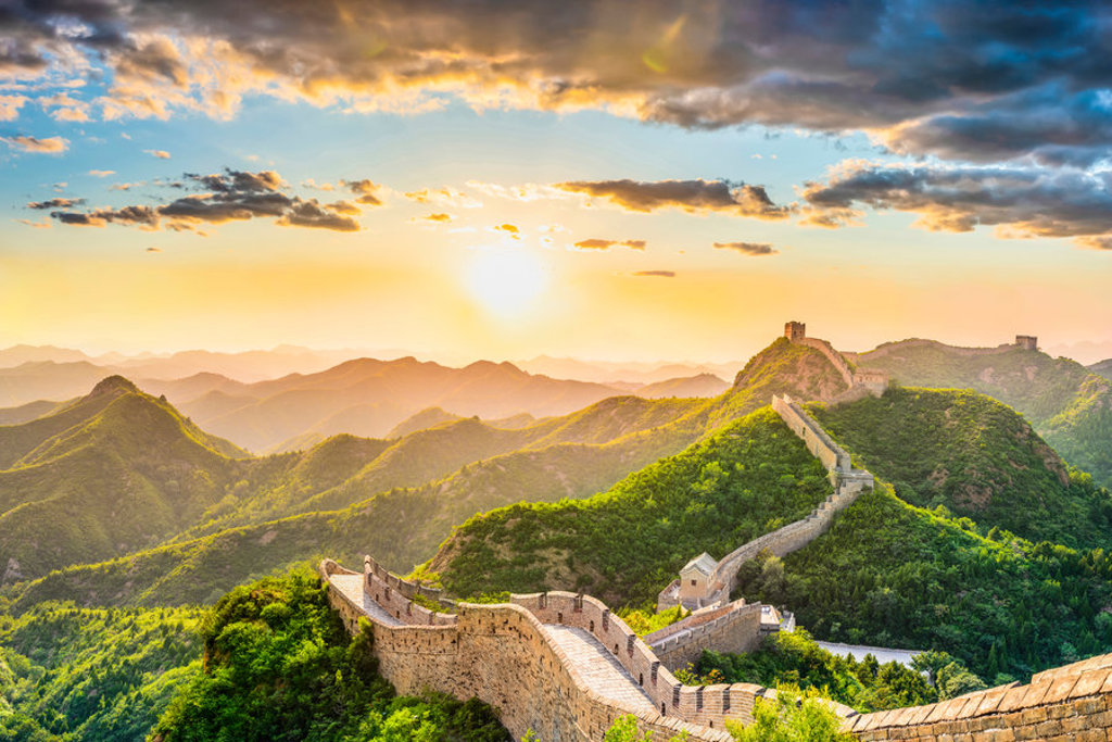 De Chinese Muur slingert over groene bergen bij zonsondergang tijdens de Groepsrondreis China Hoogtepunten (17 dagen).