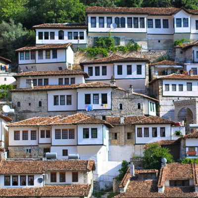 Traditionele Ottomaanse huizen in Berat, Albanië, met witte gevels en rode daken op een heuvel.