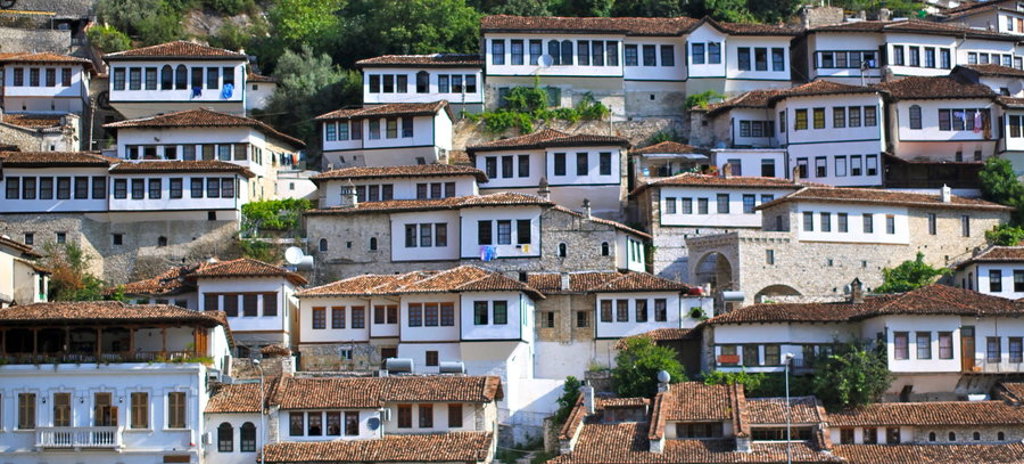 Traditionele Ottomaanse huizen in Berat, Albanië, met witte gevels en rode daken op een heuvel.