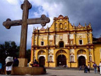 Grote houten kruis voor de gele façade van de kathedraal van San Cristóbal de las Casas, Mexico.
