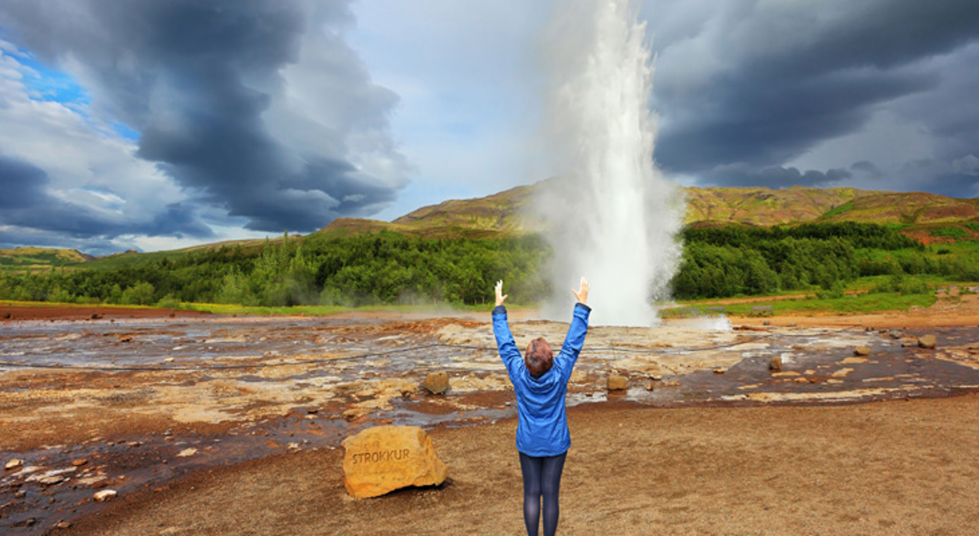 Bezoeker kijkt naar de uitbarstende Strokkur-geiser in IJsland.