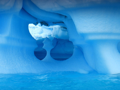 Blauwe ijsberg met uitgesleten boog en ijsgrot boven zee in Antarctica tijdens de route vliegen en varen.