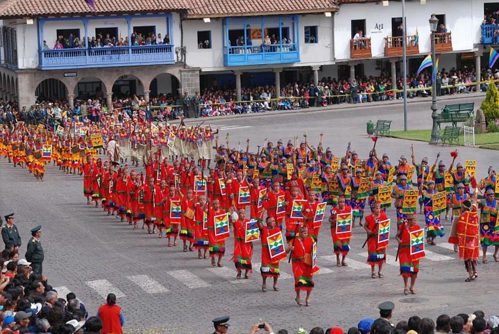 Kleurrijke parade met dansers in traditionele kleding op een plein in Cusco, tijdens een groepsrondreis Peru.