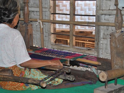 Vrouw weeft kleurrijke stof op een traditioneel weefgetouw op Lombok tijdens de route Java, Bali, Lombok & Gili Air.